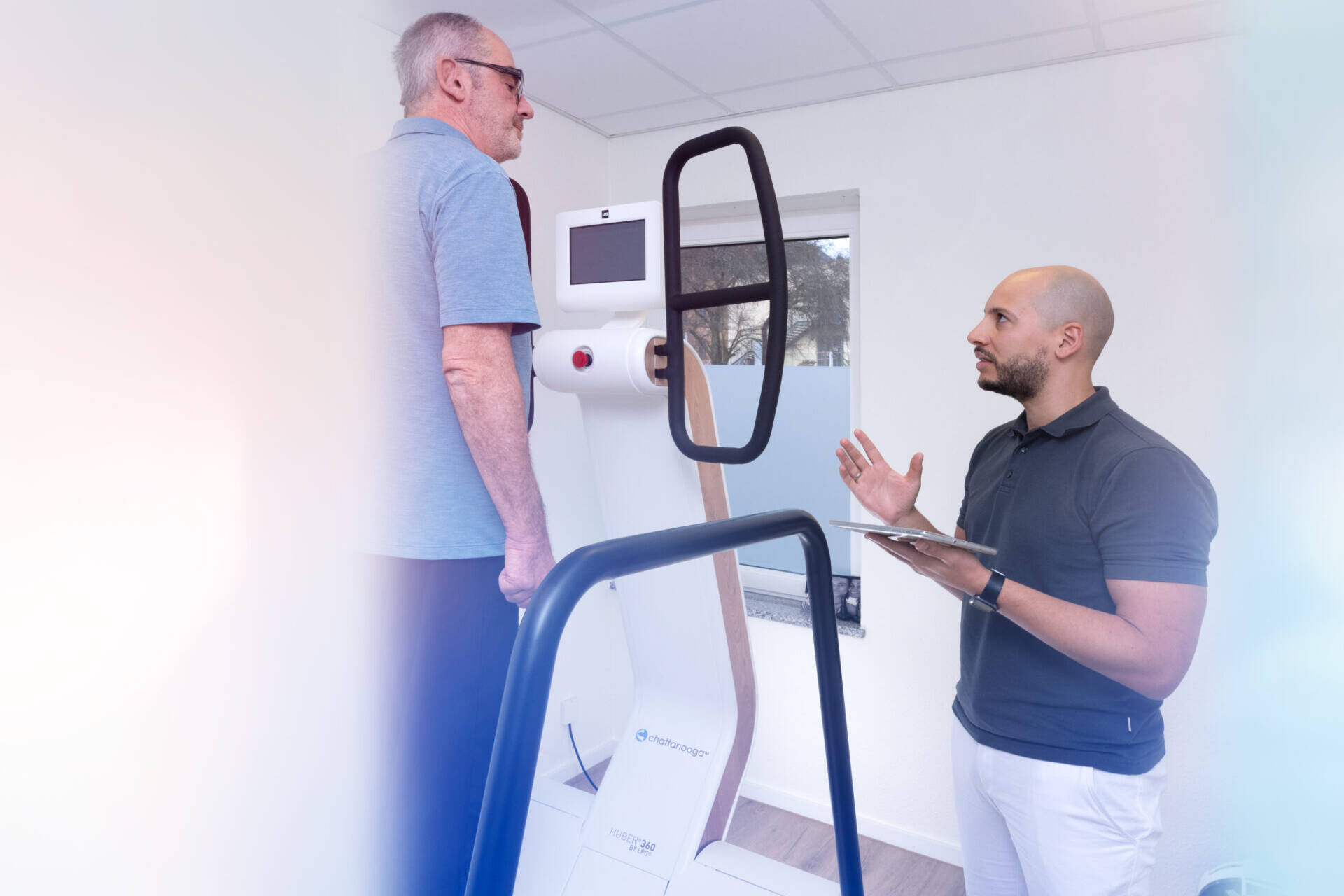 Dr. rer. med. Florian Beaudouin im Gespräch mit einem Mann an einem Gerät mit Haltegriffen
